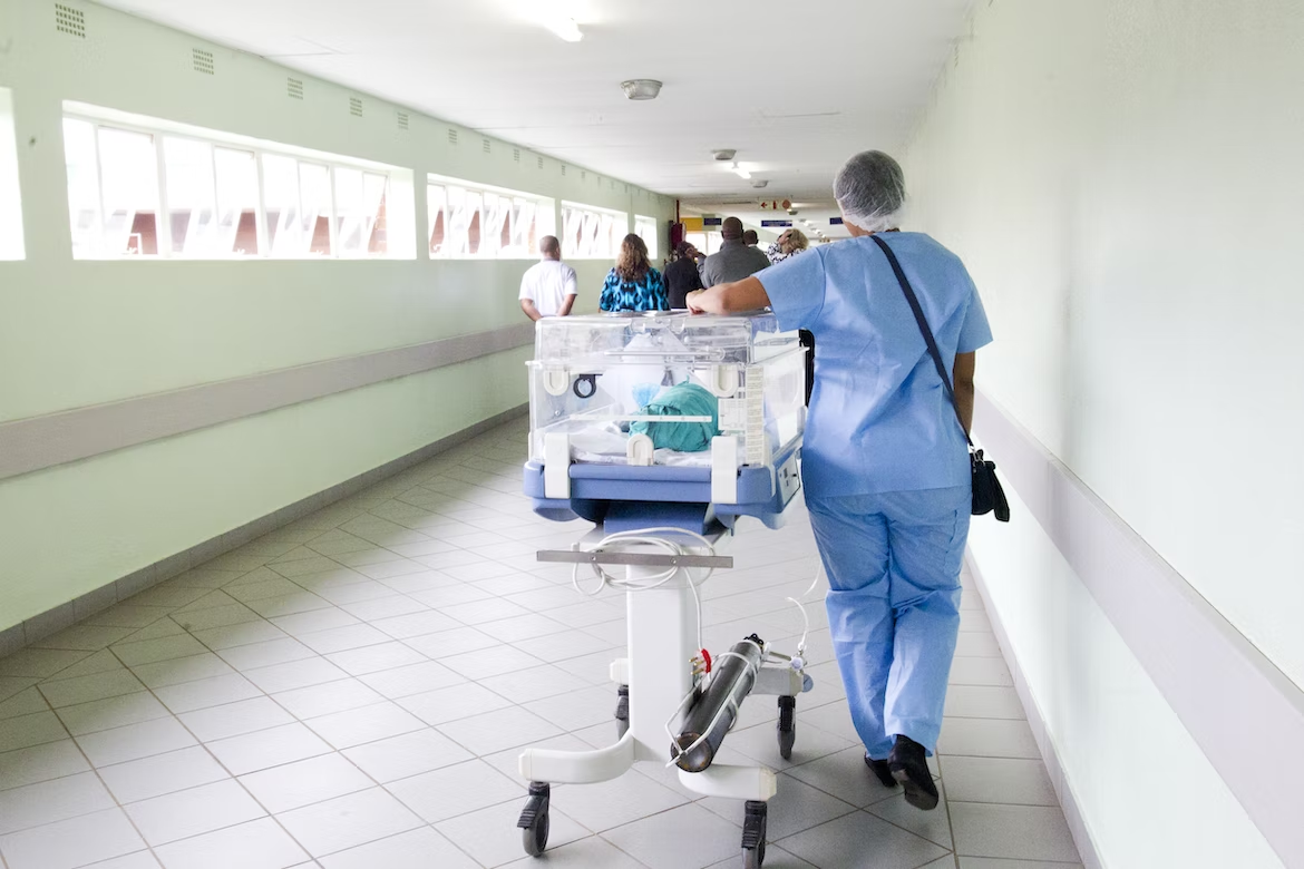 A healthcare worker moving a cart down a hallway