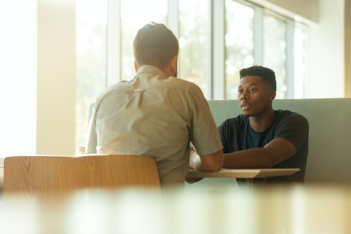 Two men sit at a table and have a discussion - Explore Career Pathways with Informational Interviews
