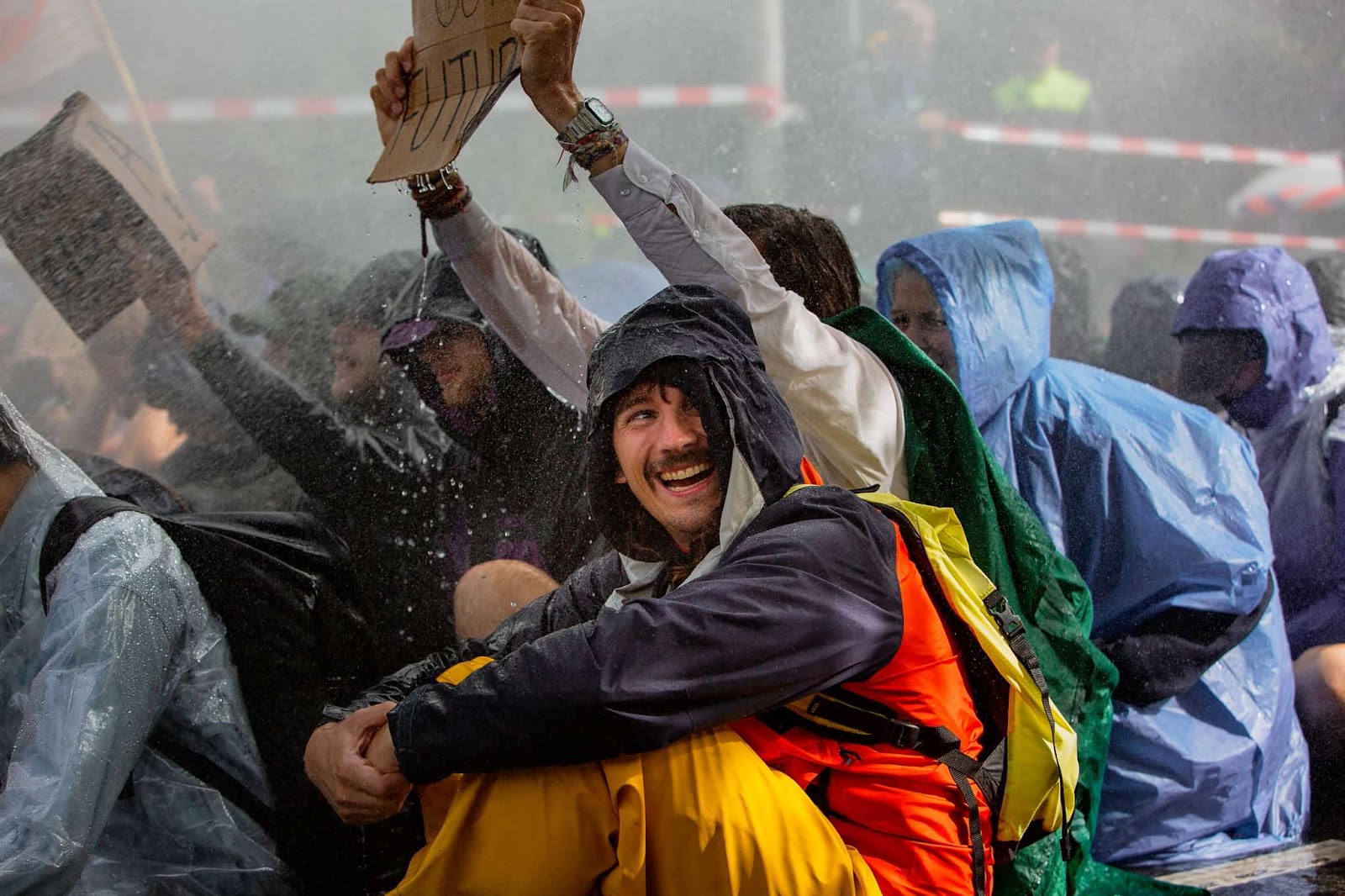 A rebel in waterproofs laughs as police spray protesters during the A12 blockade