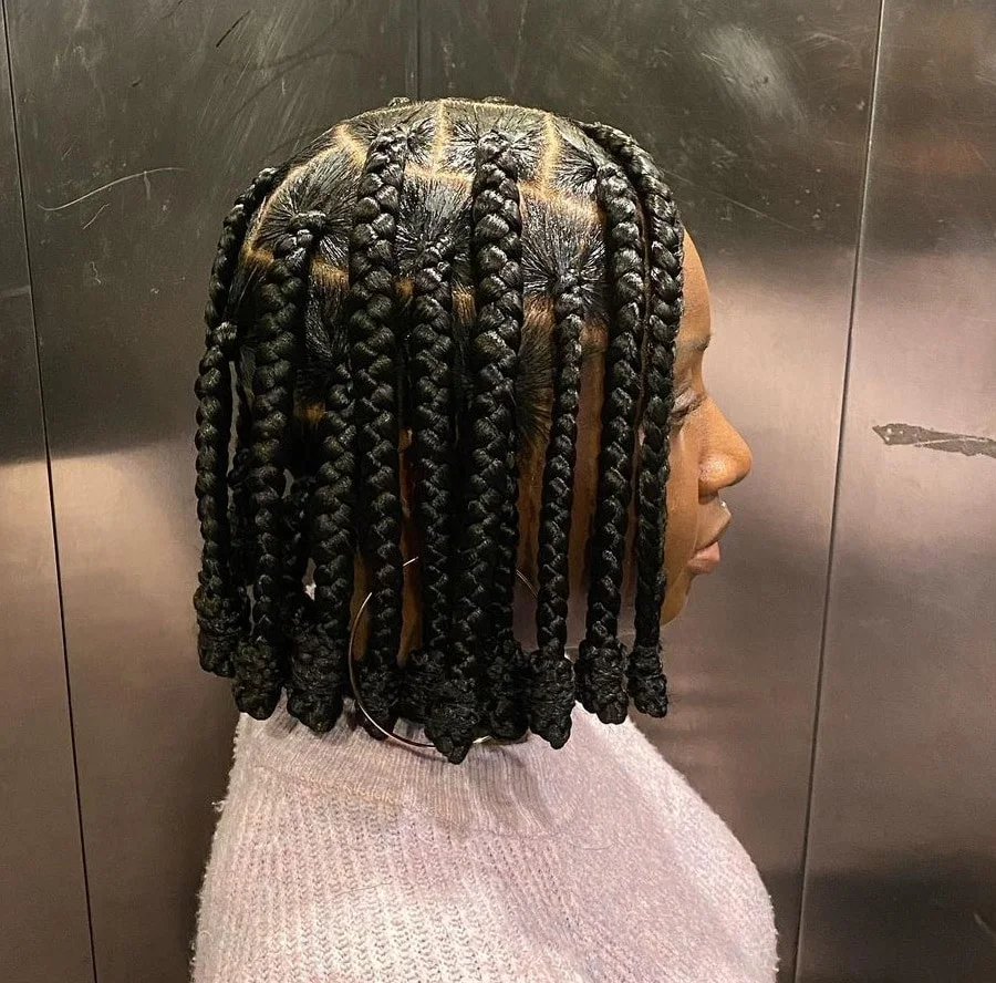 Side view of a lady rocking the jumbo  braids with knotted ends 