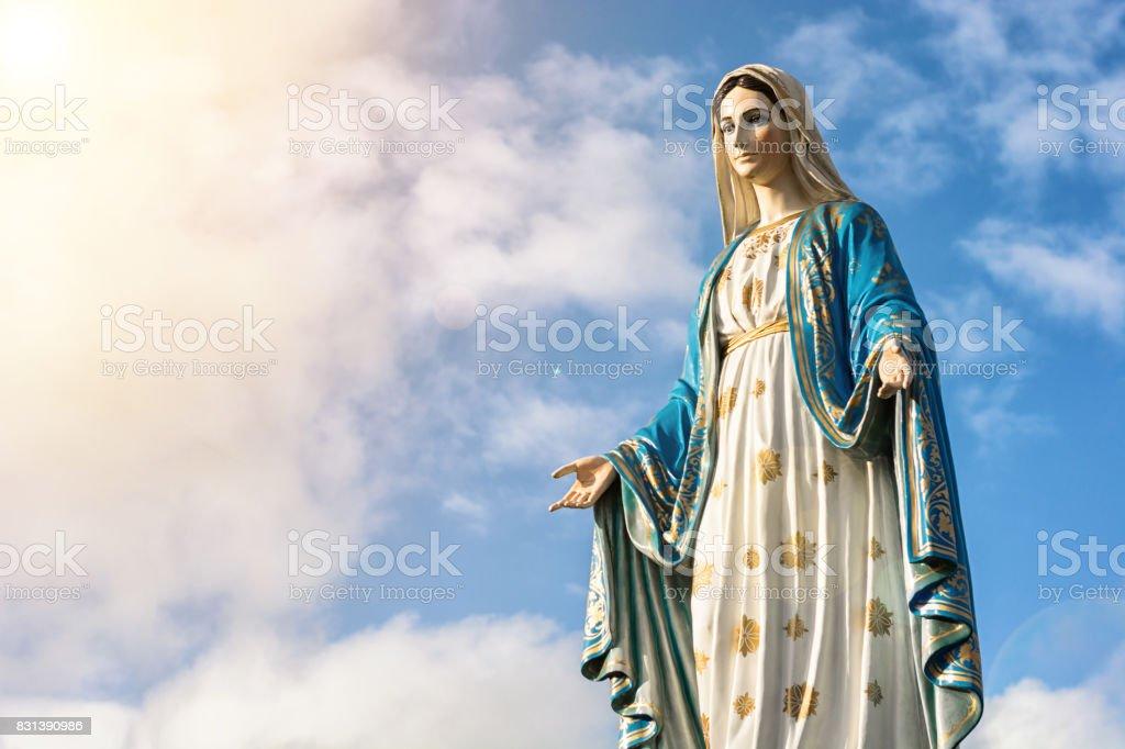 Descripción: Estatua de Virgen María con el fondo de cielo bonito - Foto de stock de La Virgen María libre de derechos