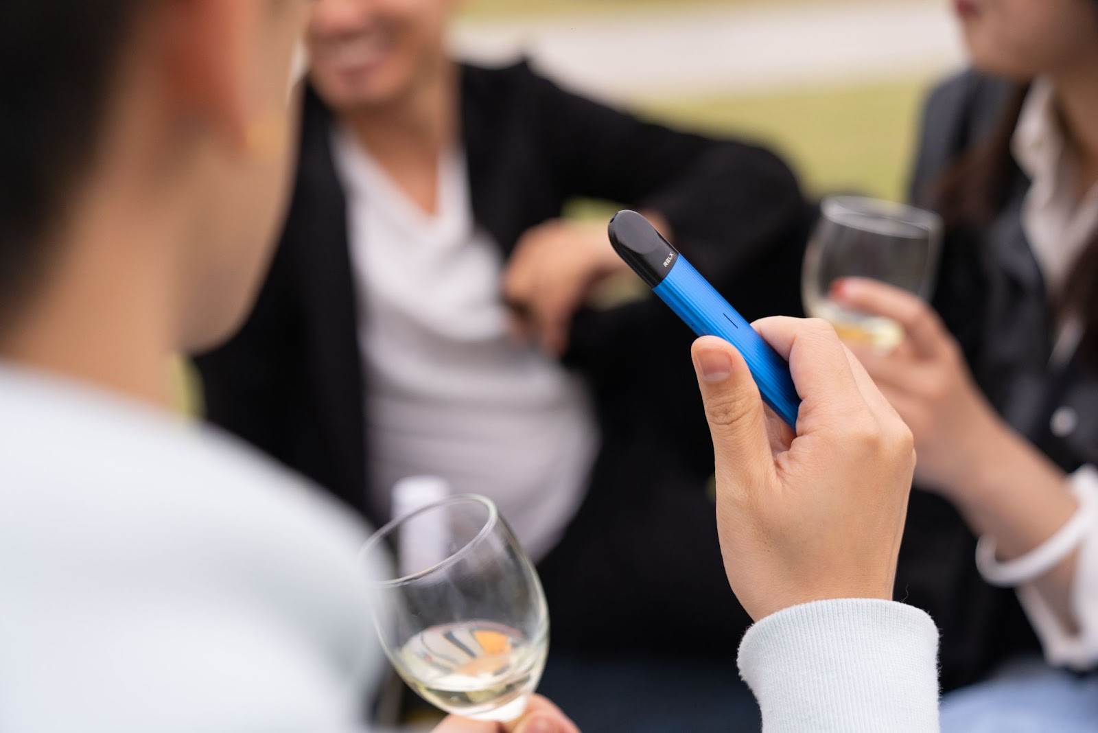 Group of people drinking wine and holding a vape device