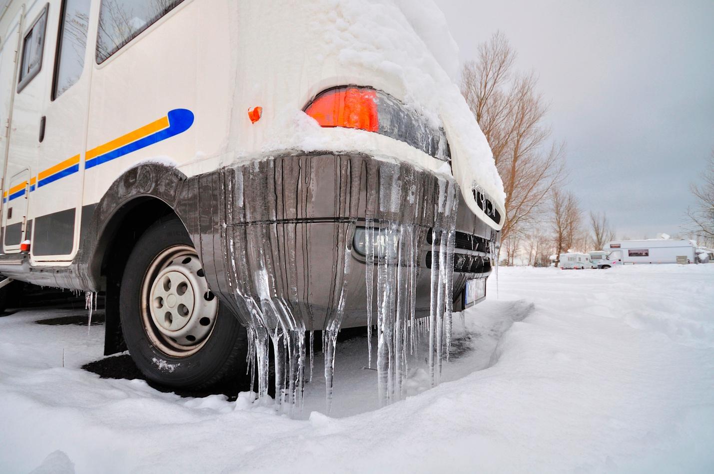 An RV parked in extreme conditions, noted most visibly by the icicles forming on its bumper.