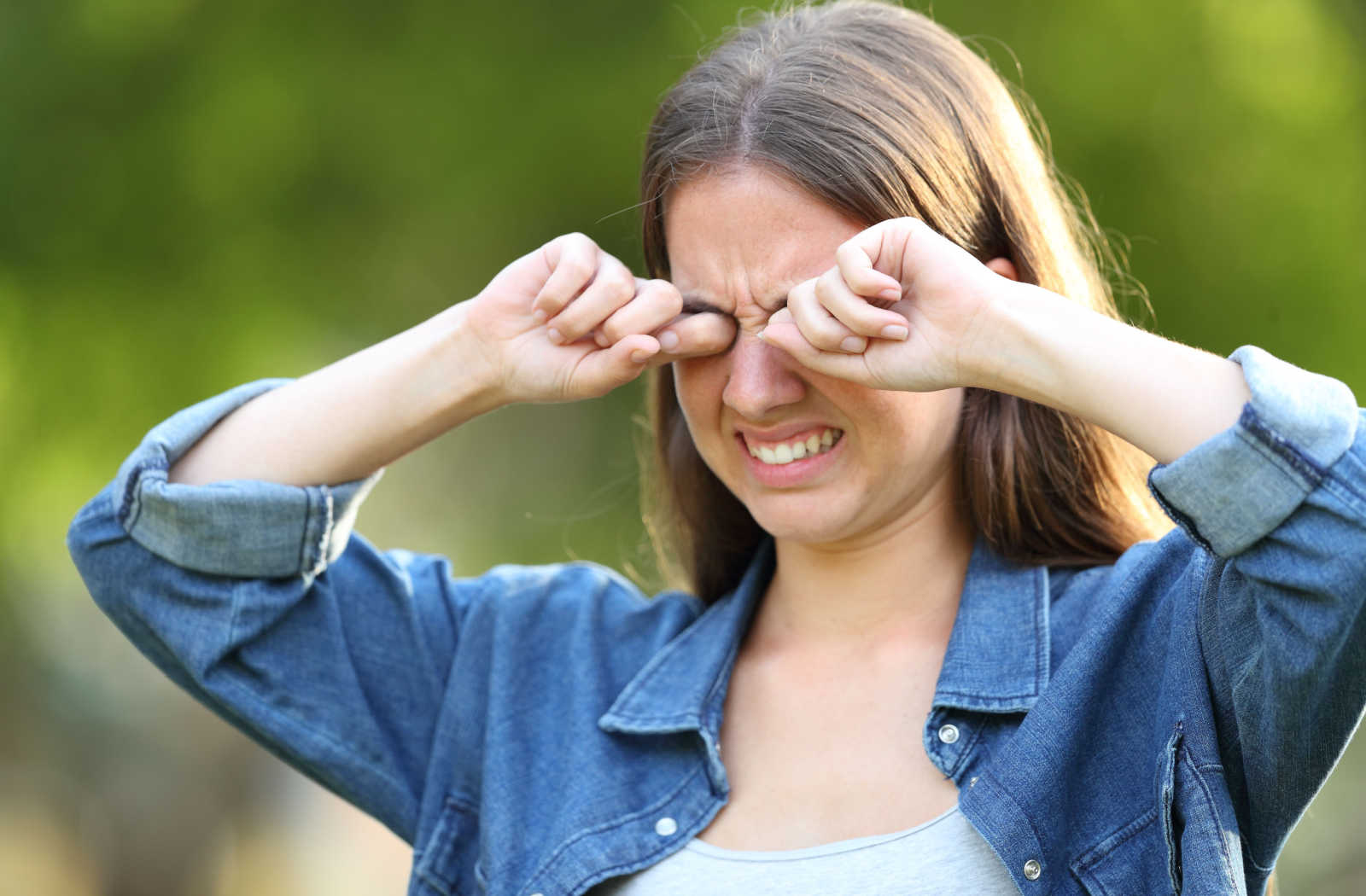 A woman vigorously rubbing both her eyes as she suffers severe itchiness due to an eye allergy.