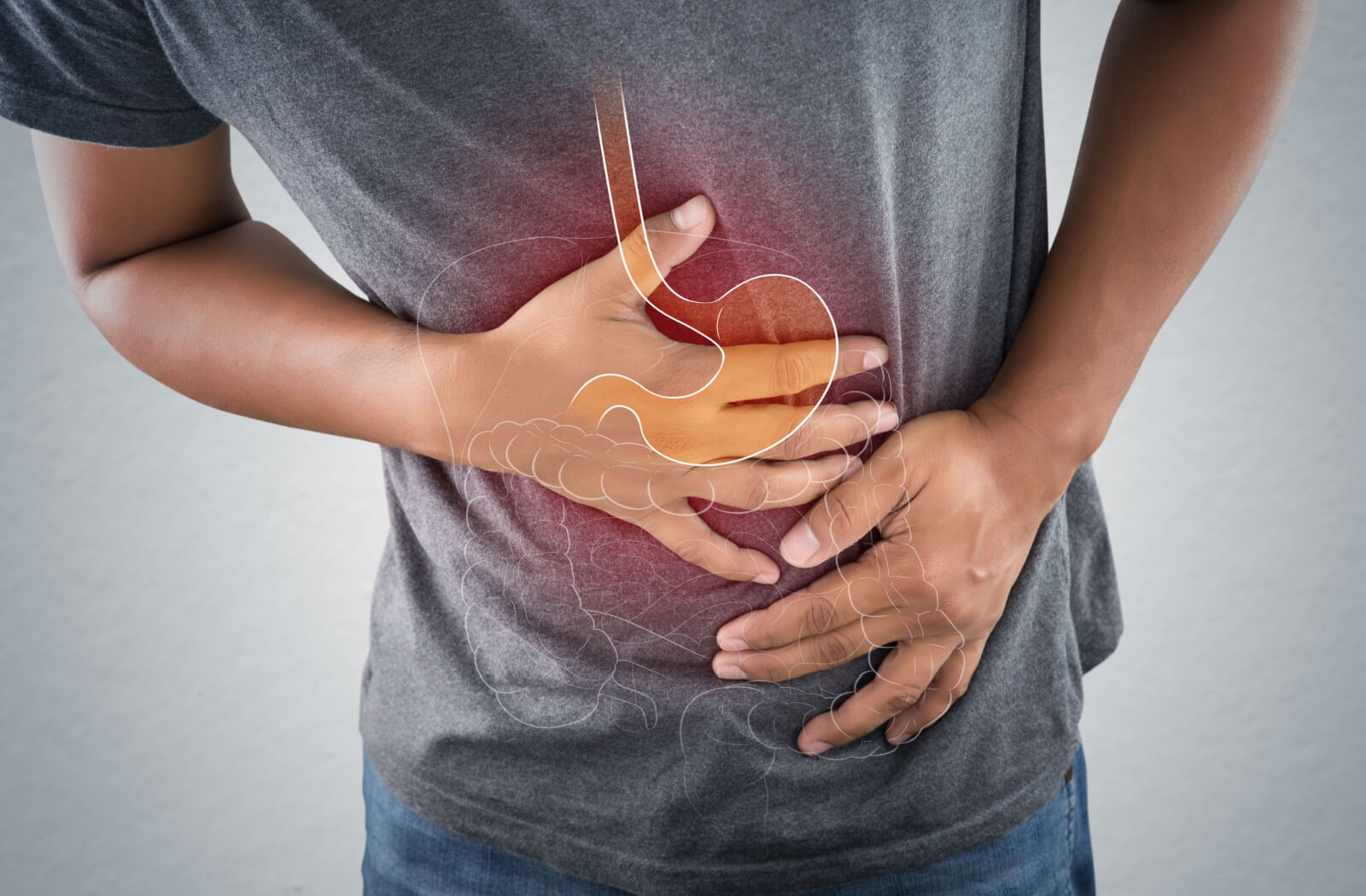 A man is touching his stomach due to pain he is experiencing because of an ulcer. Bacteria that cause stomach ulcers can also trigger bad breath.