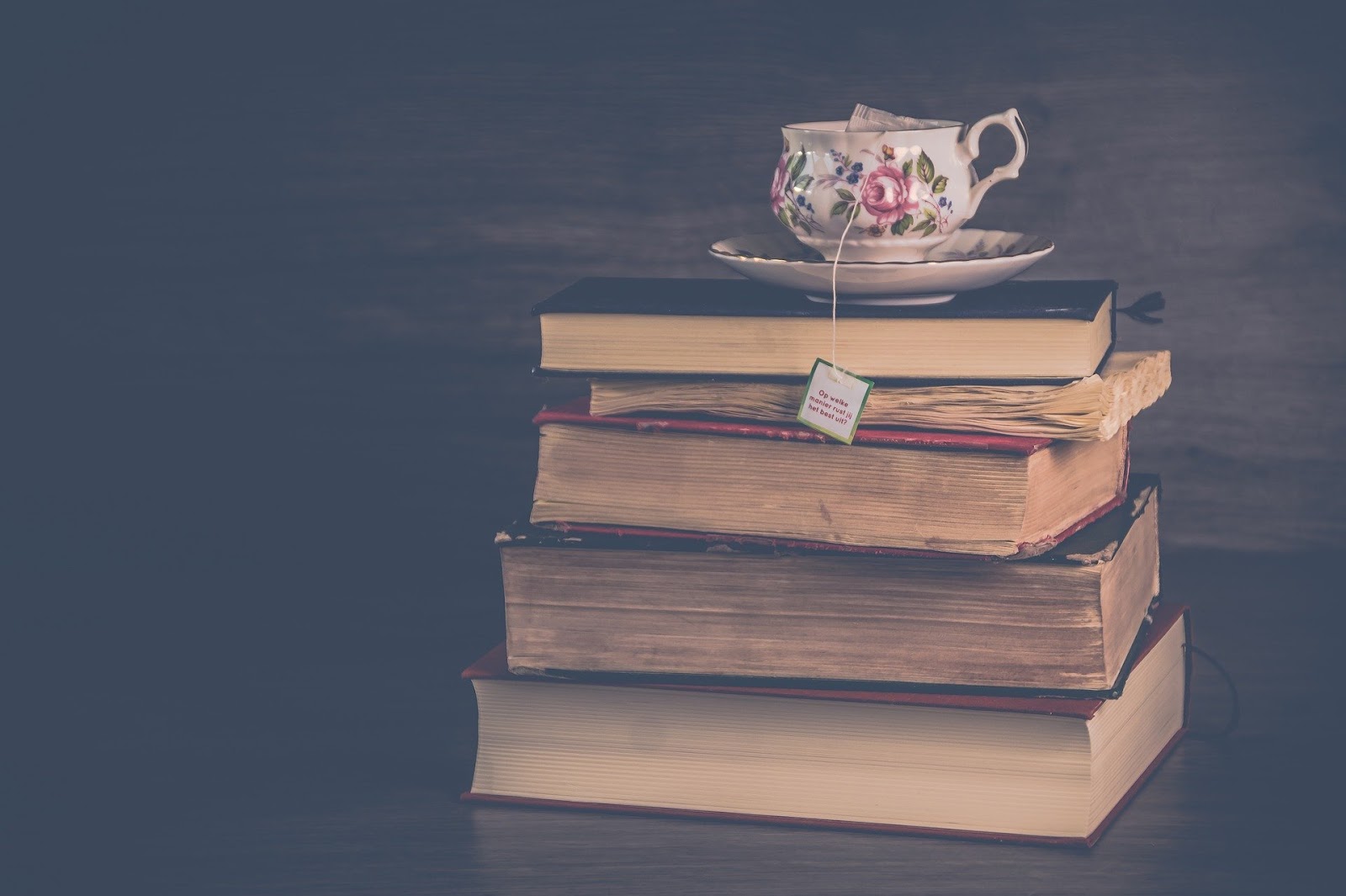 Stack of books on table with a tea cup on top