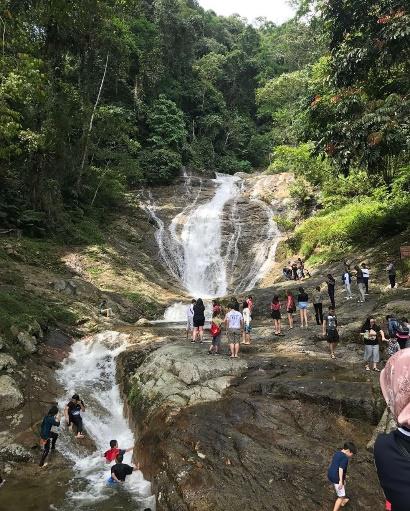 A group of people standing next to a waterfall

Description automatically generated