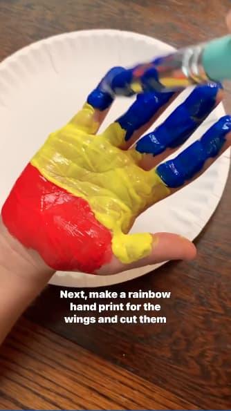 Child painting hand with rainbow colors
