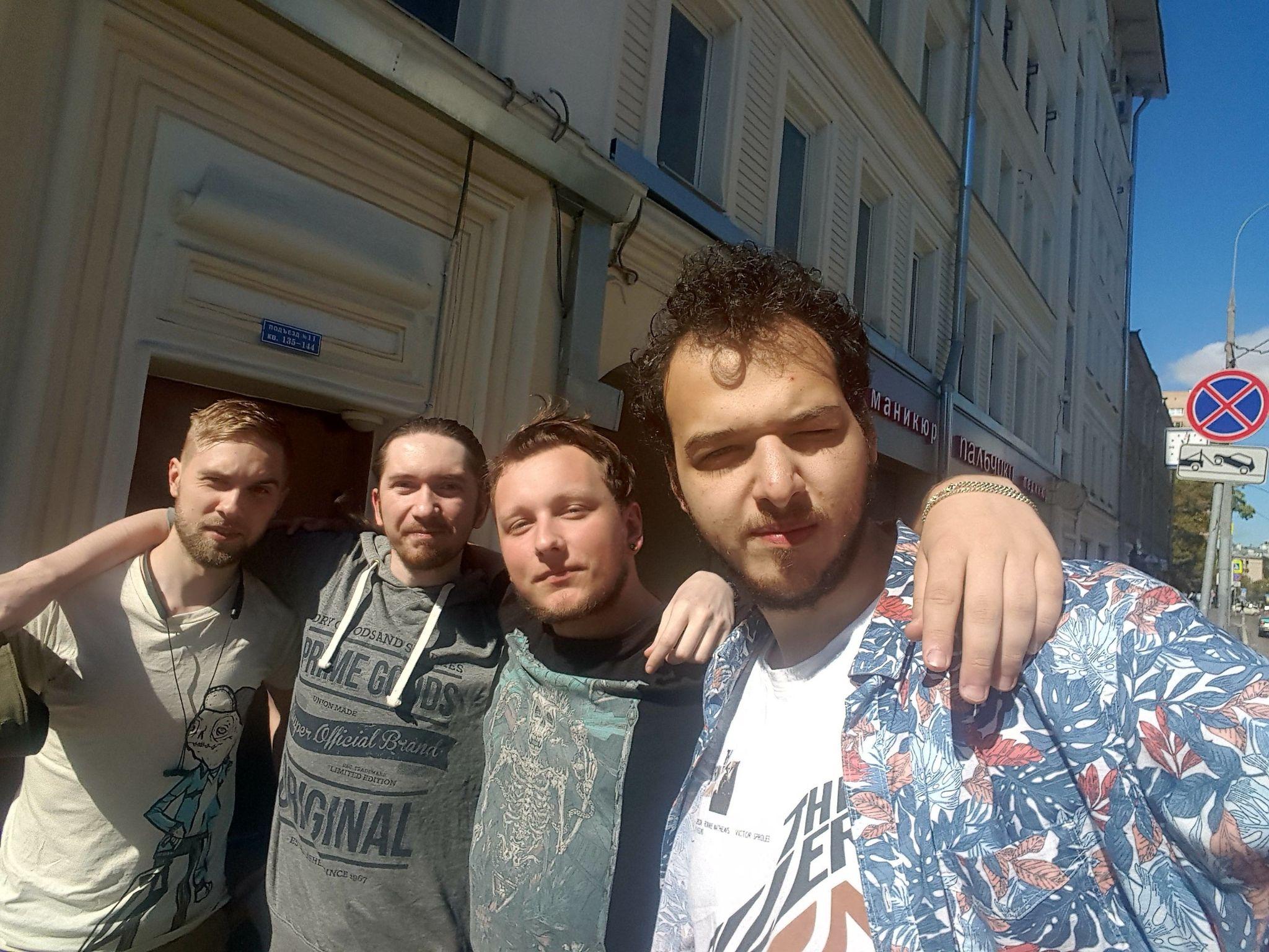 Four individuals pose for a picture together outside near a building.