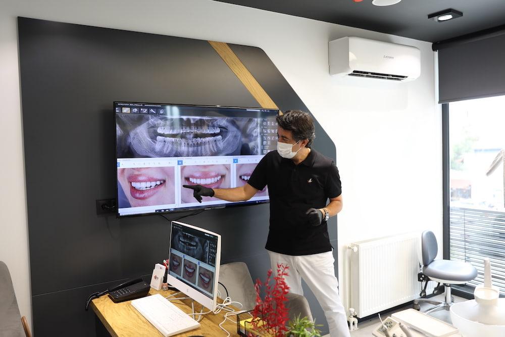 Dentist examining full mouth dental implant treatment on screen