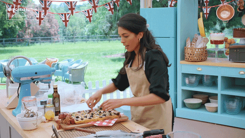 A gif of a baker on The Great British Baking Show steps away from her station after time’s up.