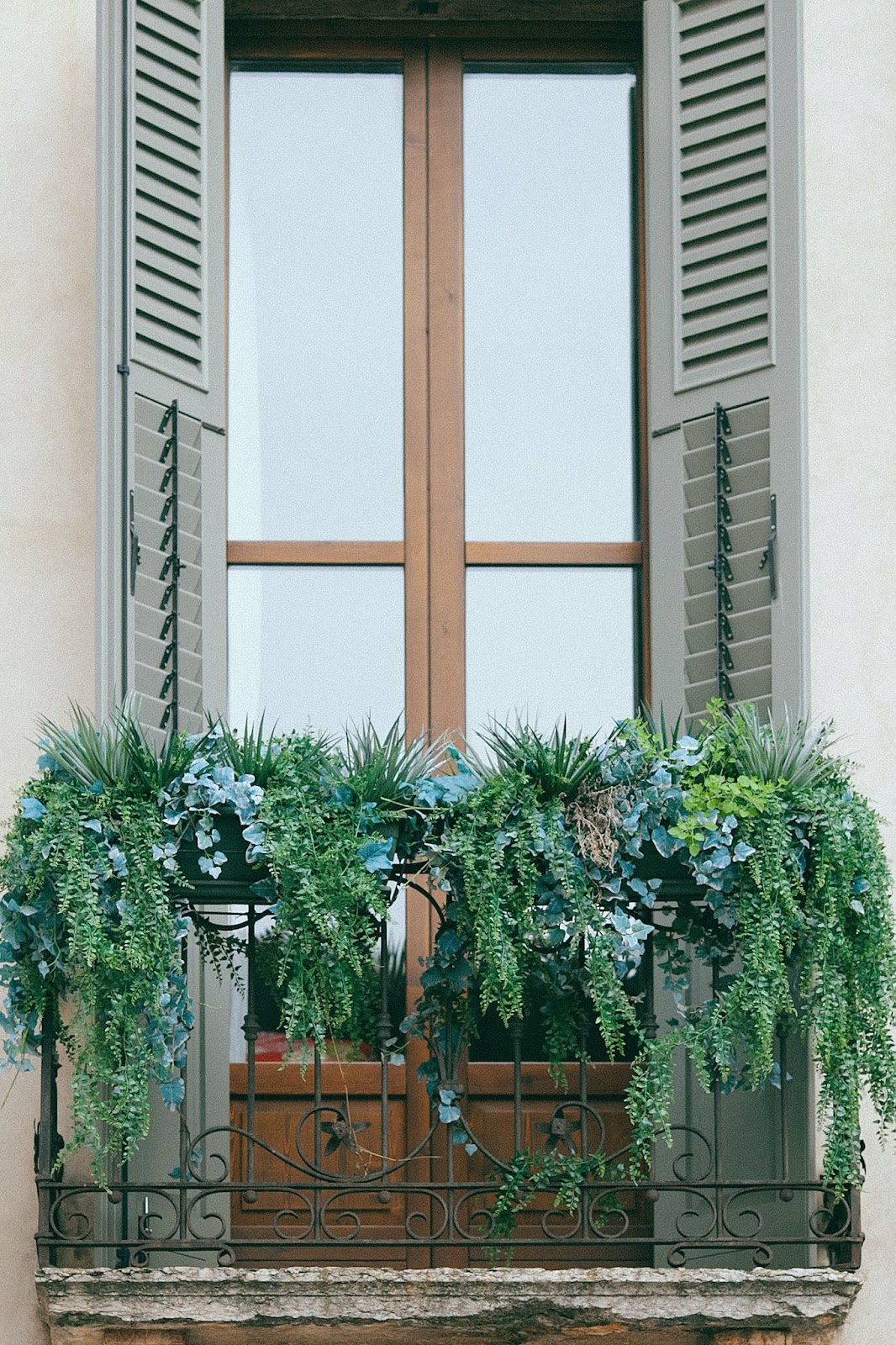 Small balcony with its railing decorated with hanging plants