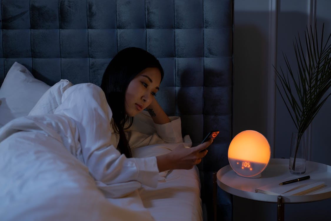 a woman lying in bed while using phone