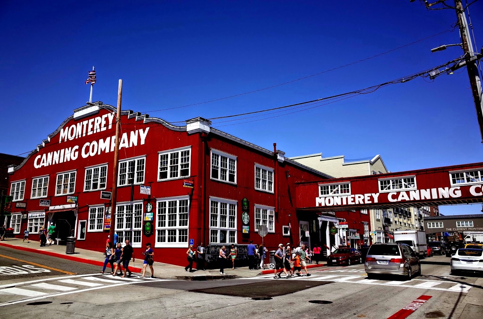 monterey canning company big red building and two pedestrian crossings with people on a clear summer day in california