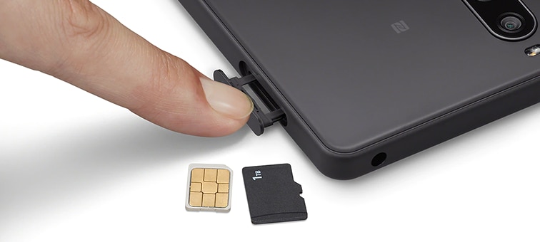 Close-up on someone using their finger to access the SIM tray on the Xperia 10 IV, plus a SIM card and an SD card