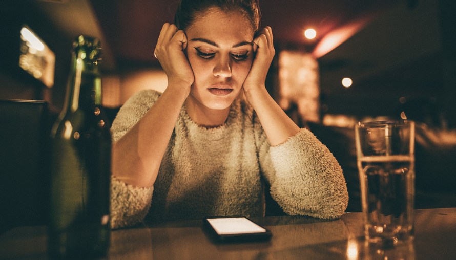 girl at a bar staring at her phone