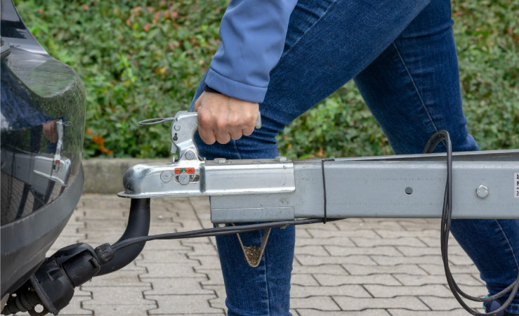 A woman attaching a trailer to her car’s trailer hitch