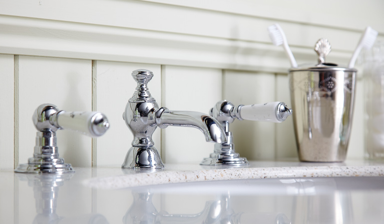 A bathroom sink with a high-end stainless steel faucet and matching toothbrush holder