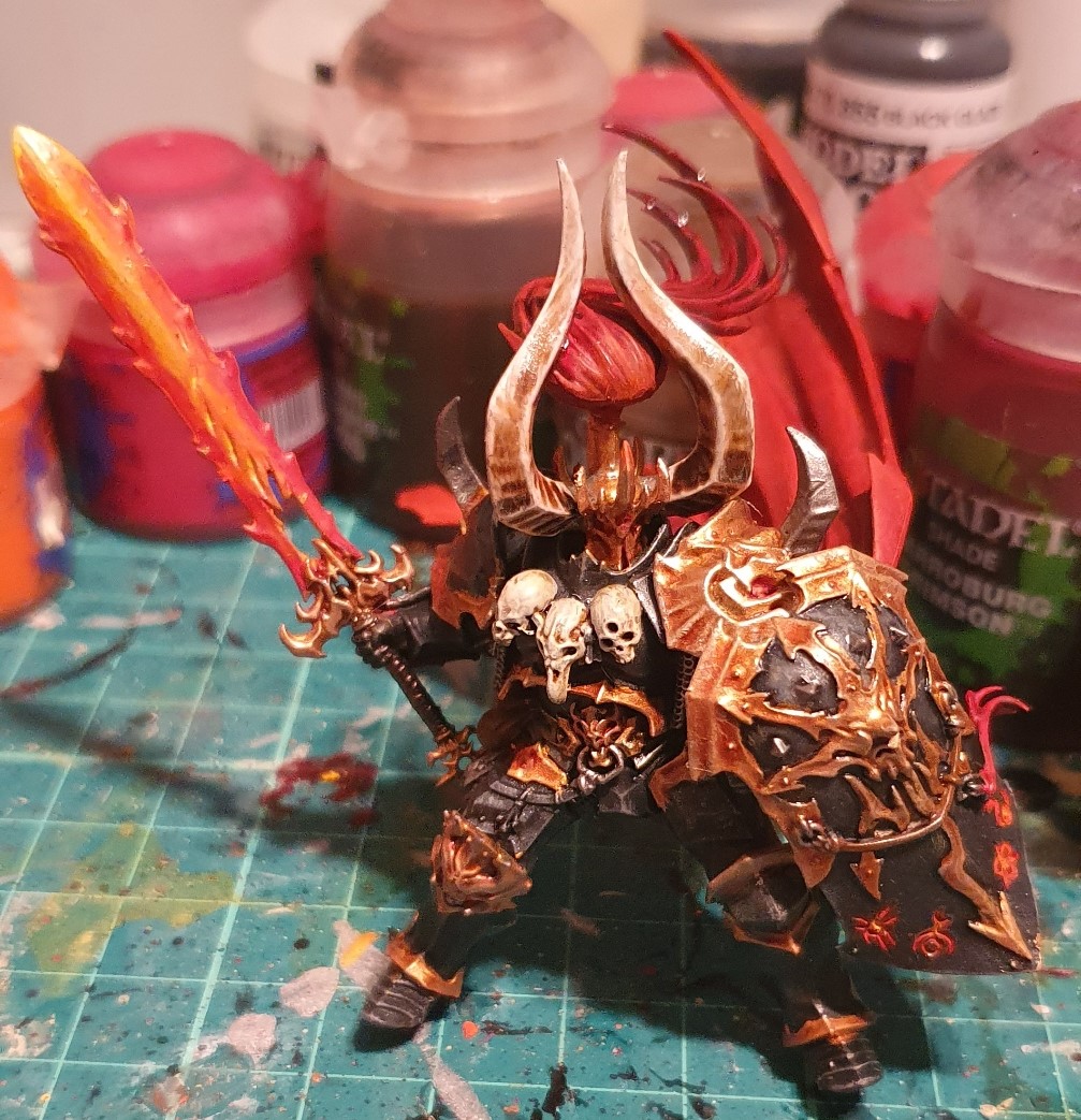 Archeon the Everchosen on his own, showing gunmetal with gold trim armour, red cape and glowing red and orange sword and runes.