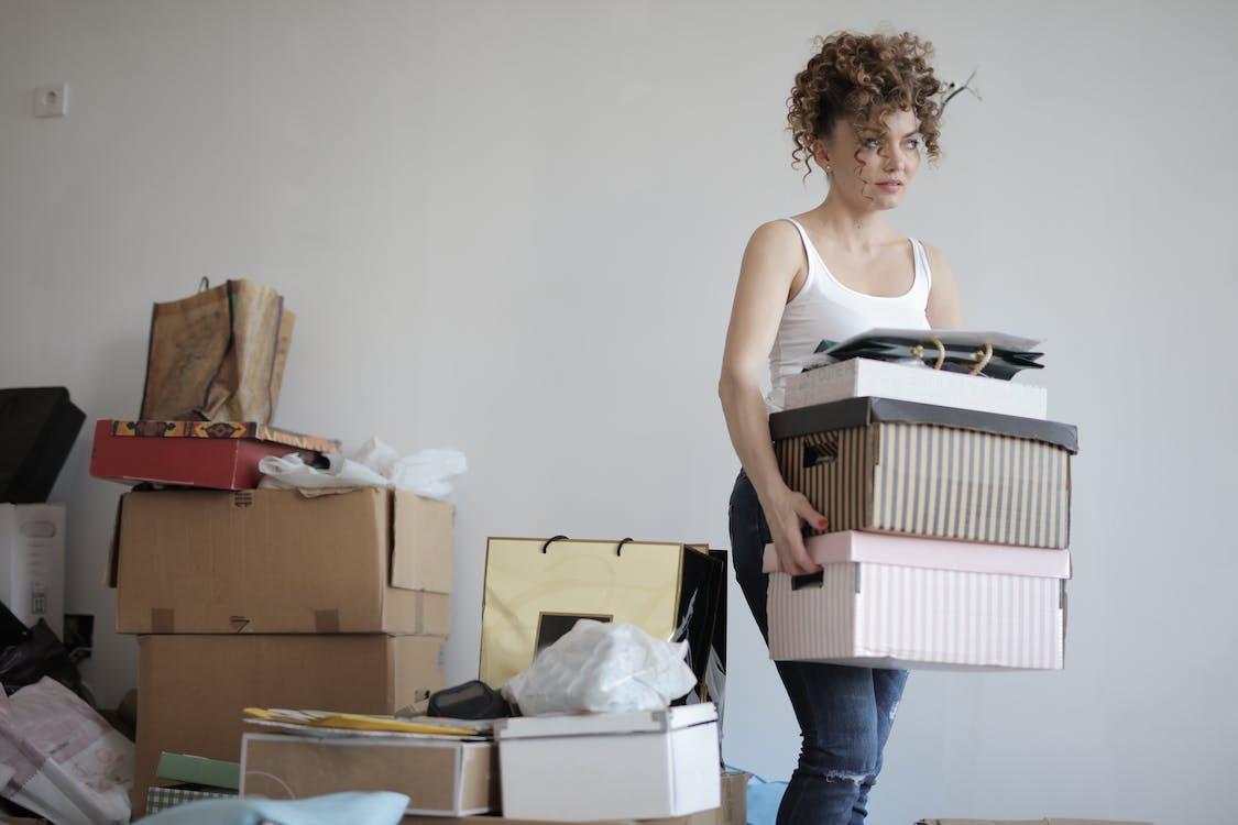 Free Concentrated woman carrying stack of cardboard boxes for relocation Stock Photo