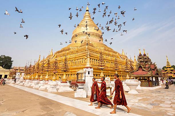 View of Shwezigon Pagoda in Bagan, Myanmar Bagan, Myanmar - March 15, 2014: Novice Buddhist monks walking around the sacred Shwezigon Paya, one of Myanmar's most revered pagodas, in Nyaung U, Bagan, Myanmar (Burma). Shwezigon Pagoda stock pictures, royalty-free photos & images