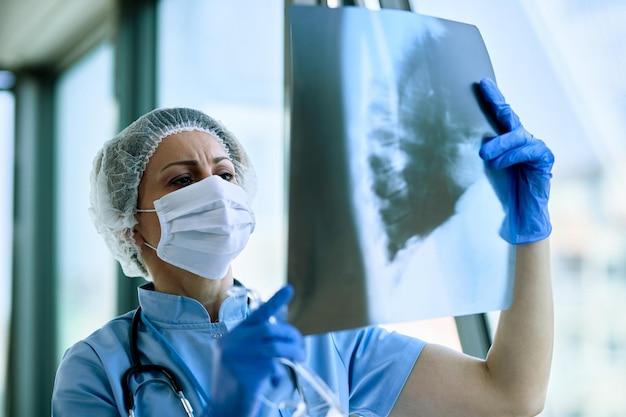 Radiologista feminina analisando radiografia de tórax de um paciente na clínica médica, analisando se há alguma doença no sistema respiratório