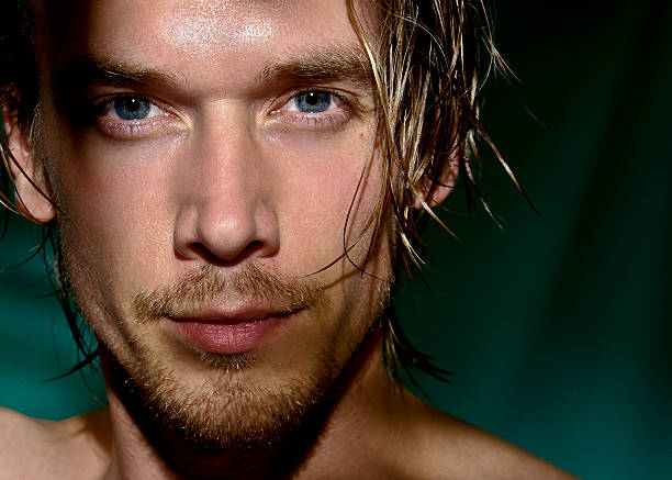 Closeup portrait of a long haired man's face with blue eyes