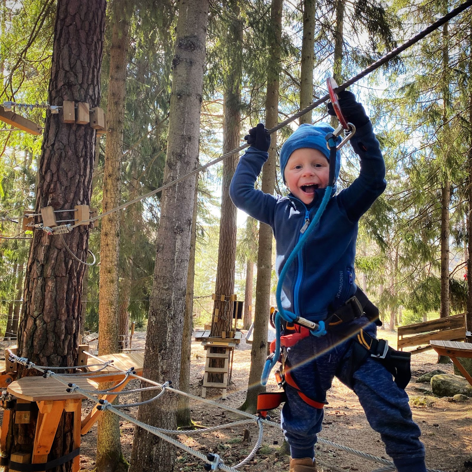 Ett barn ler och klättrar i en höghöjdsbana