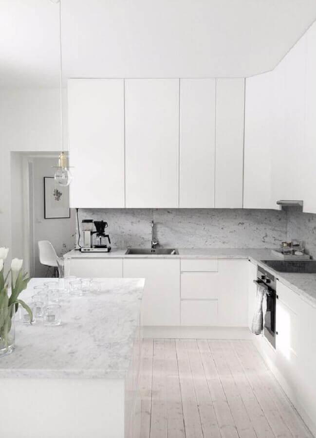 Cozinha com piso de madeira branco, armários brancos, revestimento nas bancadas e parede da pia de porcelanato reproduzindo pedras