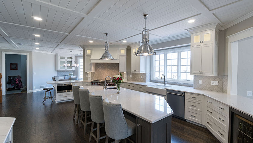 High-end-kitchen-with-white-cabinetry-quartz-countertops-coffered-ceilings-stainless-steel-appliances-large-eat-at-island