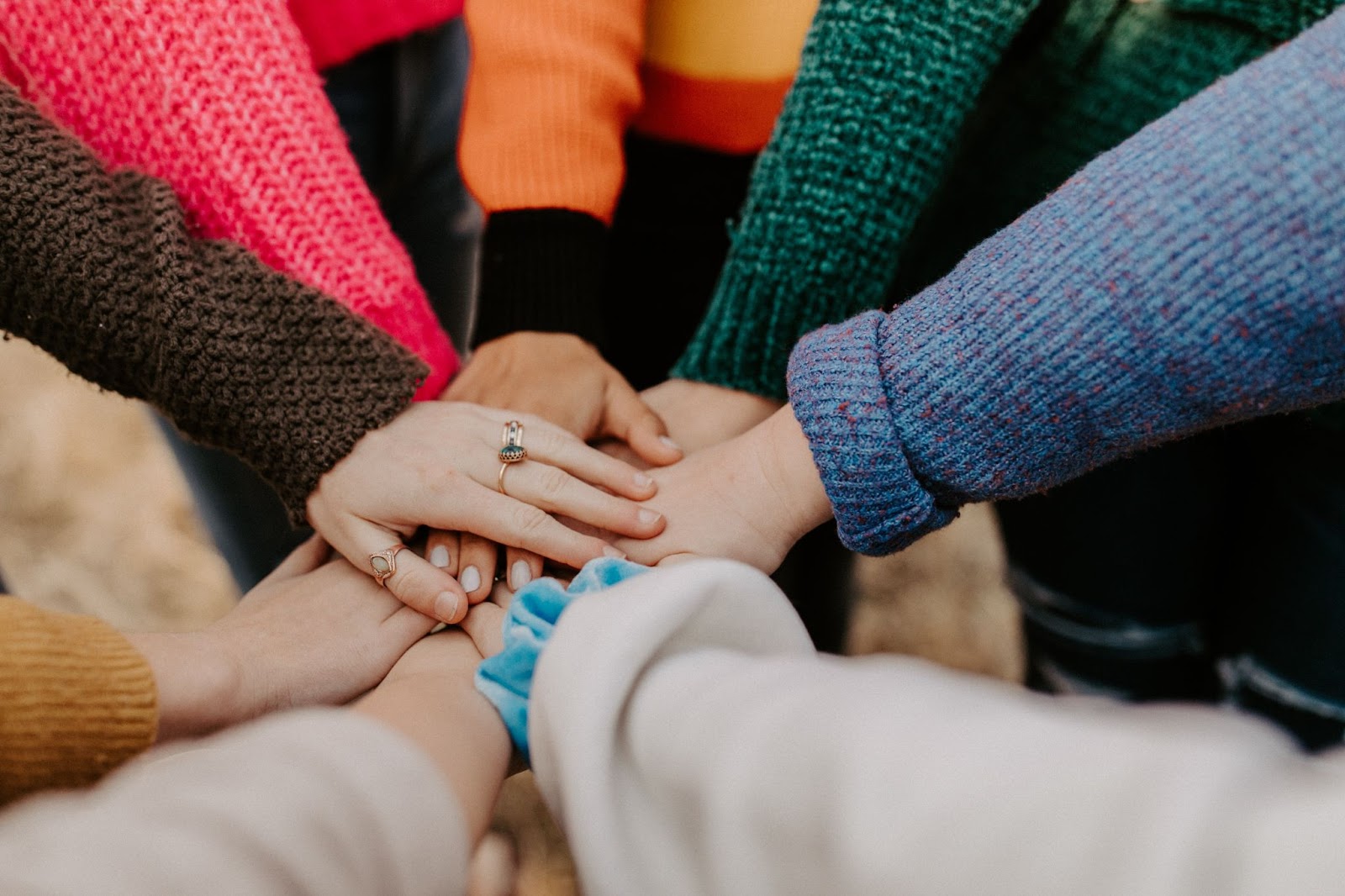 An authentic brand results in a unified message. This photo shows a group of people with their hands in the center of a circle.