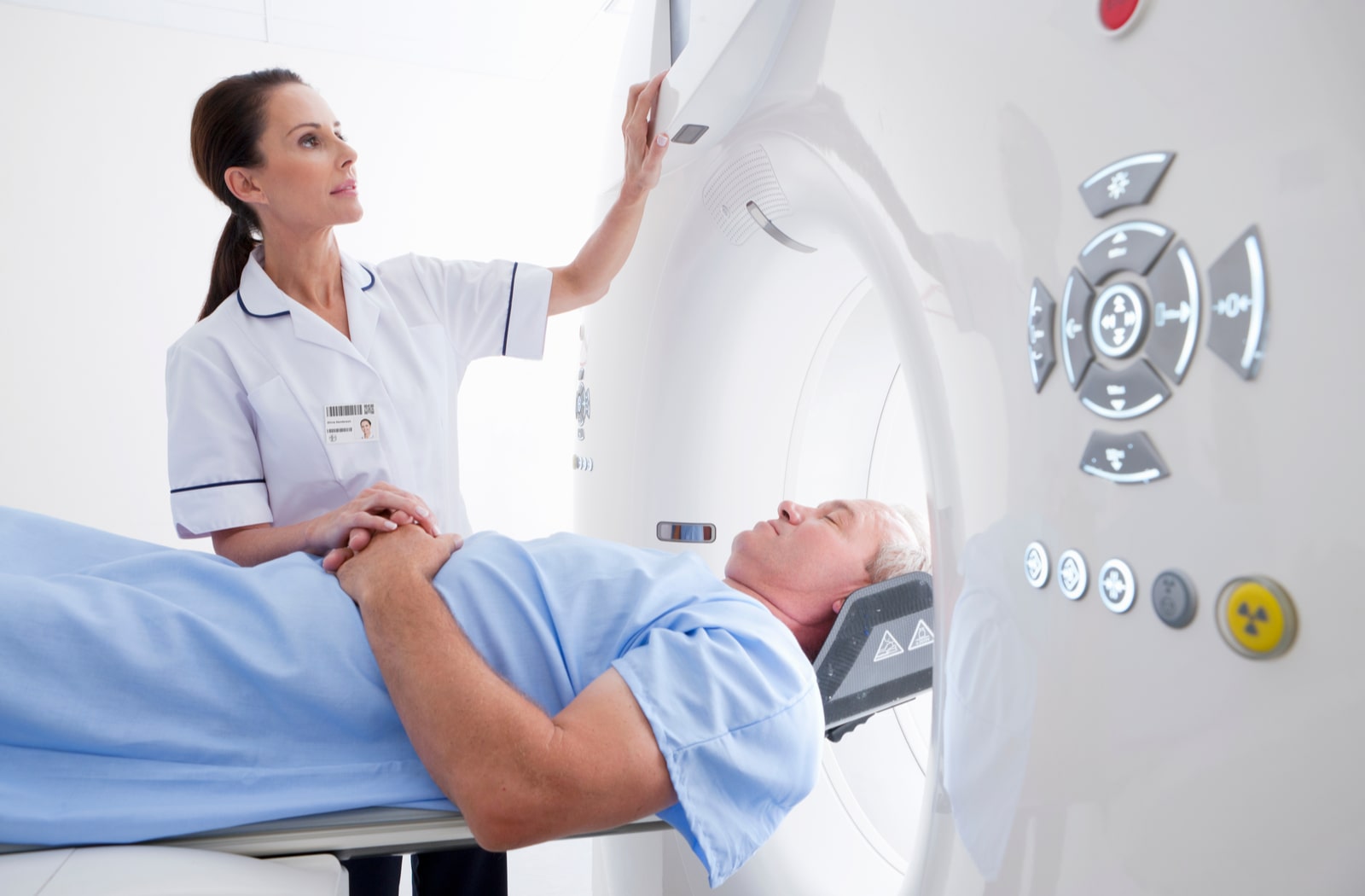 A female nurse operating a CT scanner for a male patient lying down