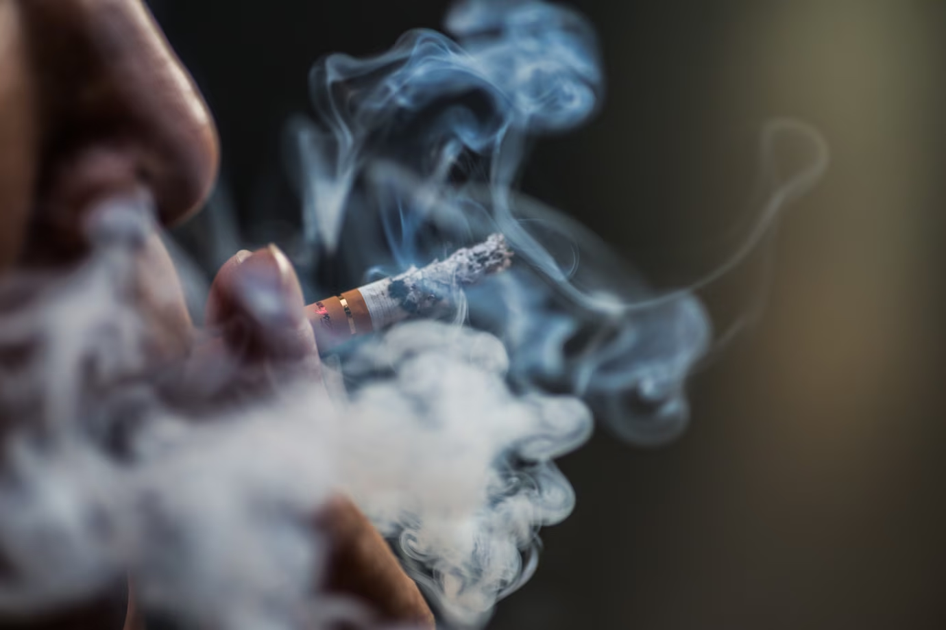 person puffing on a cigarette surrounded with smoke