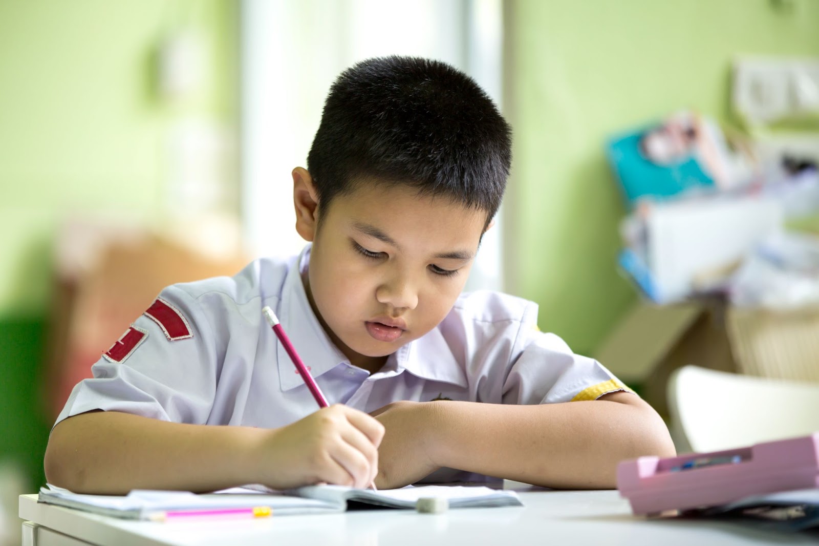 Asian boy in school uniform doing his homework at home