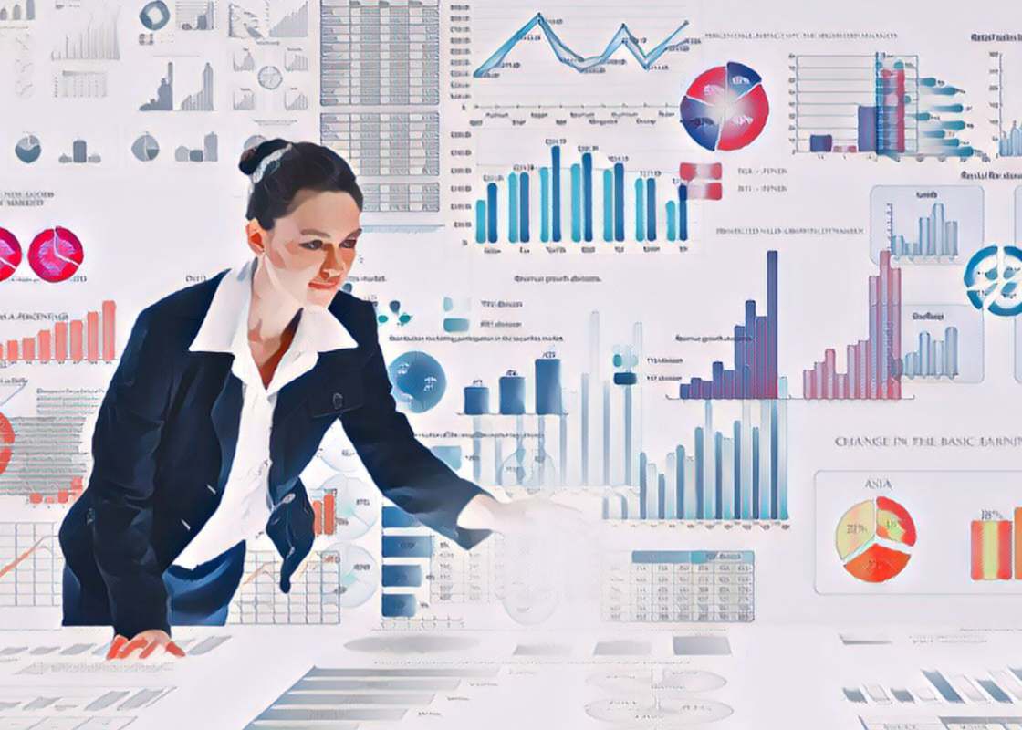 A young data driven marketing executive stands in front of charts and infographics and is pointing to one. 