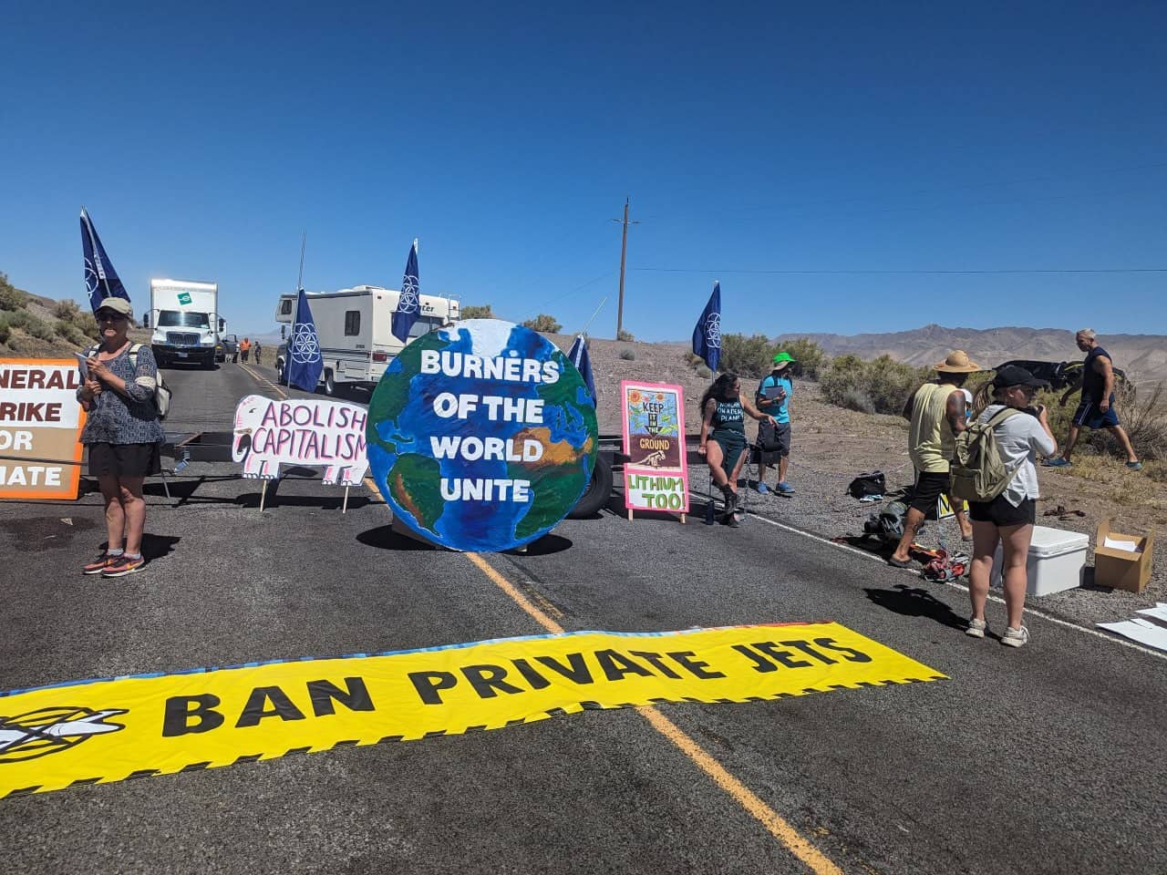 Rebels set up a barricade across the road to Burning man, including a banner demanding a ban on private jets 