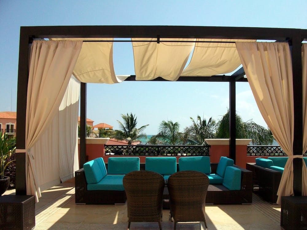 Terrace on a contemporary property with a beige fabric canopy pergola and floating curtains on the pergola