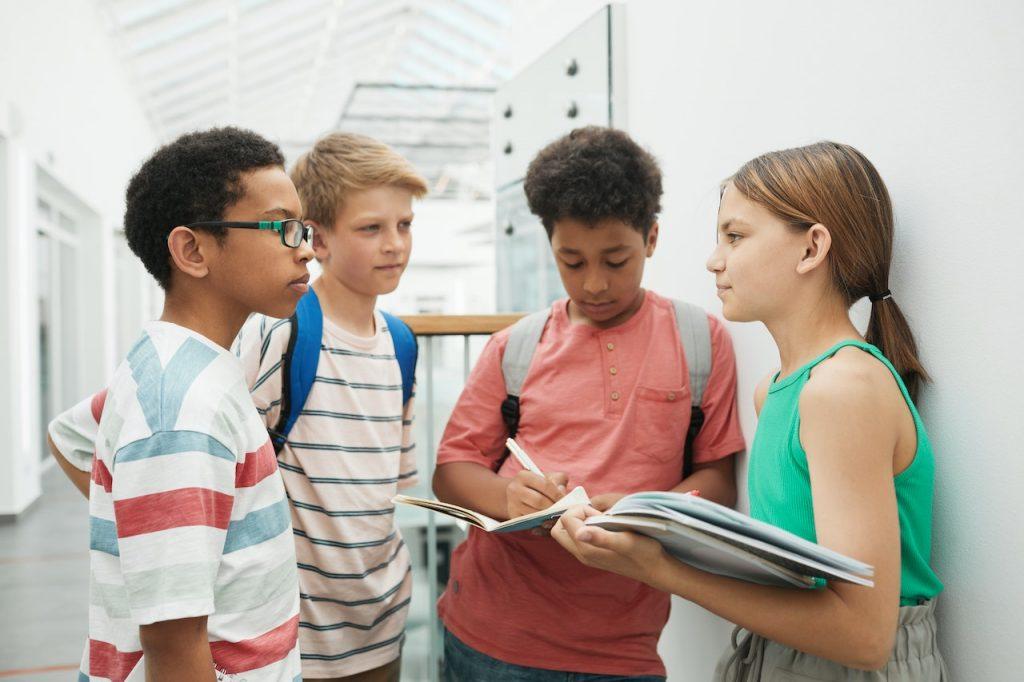 four children holding books and discussing something