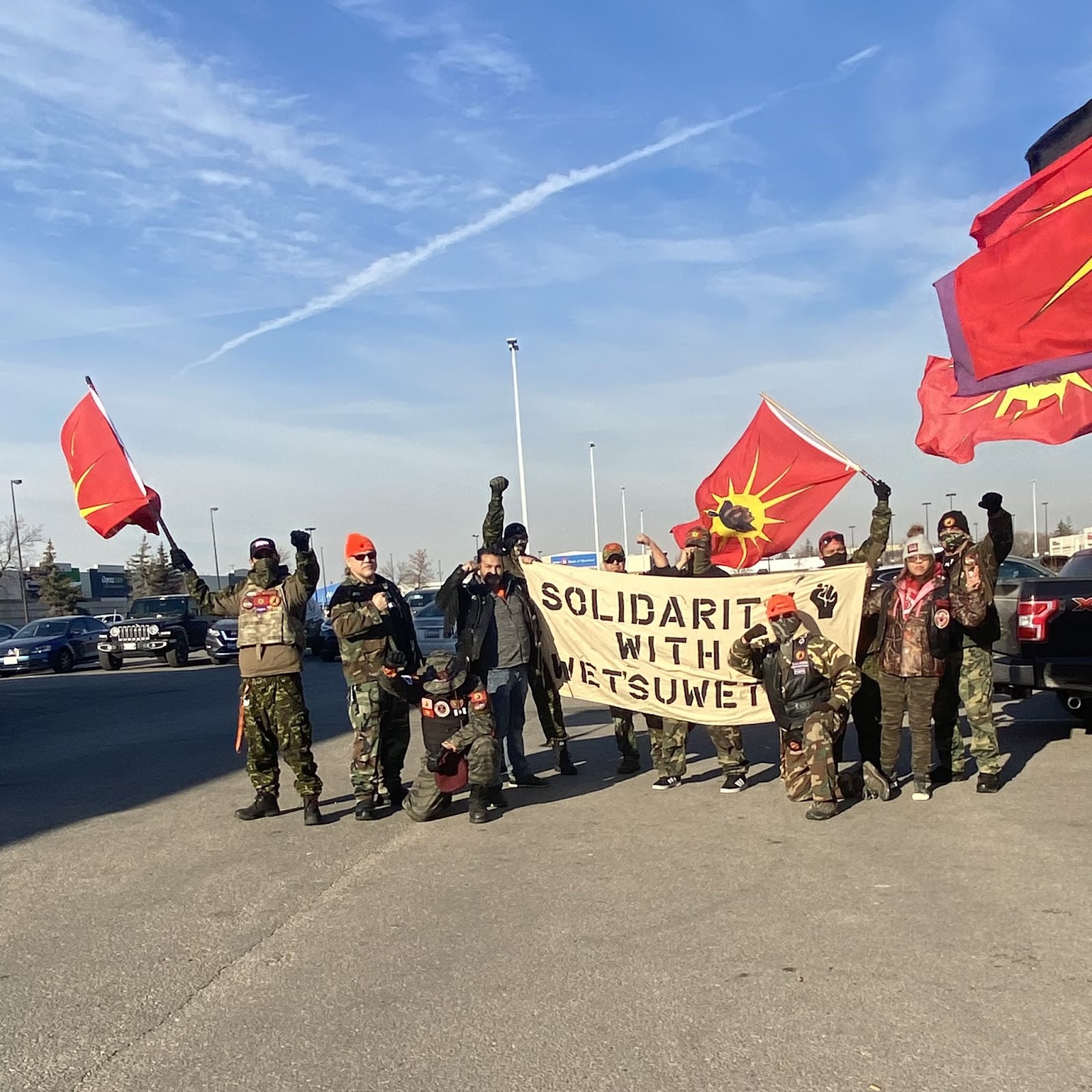 Members of the urban warrior alliance pose with fists in the air with signs and banners while blocking traffic.