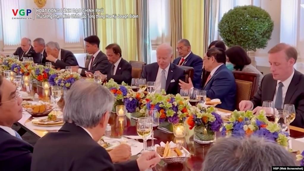 Thủ tướng Việt Nam Phạm Minh Chính trò chuyện với Tổng thống Mỹ Joe Biden trong khi các vị khách khác dùng bữa tối trong Phòng Quốc Yến tại Nhà Trắng, ở Washington, ngày 12 tháng 5 năm 2022. Ảnh chụp màn hình video do Báo Điện tử Chính phủ đăng tải.