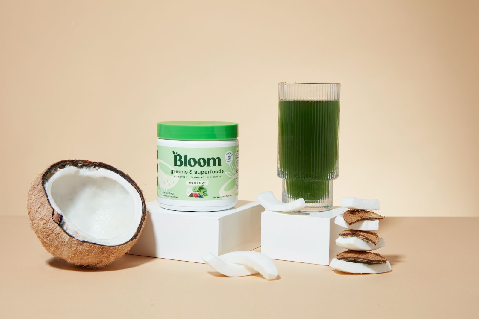 bloom nutrition products in jars with a coconut broken open next to it