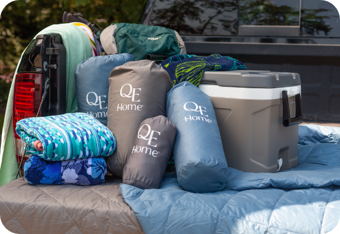 The back of a truck loaded with beach towels, packable down blankets and a cooler.