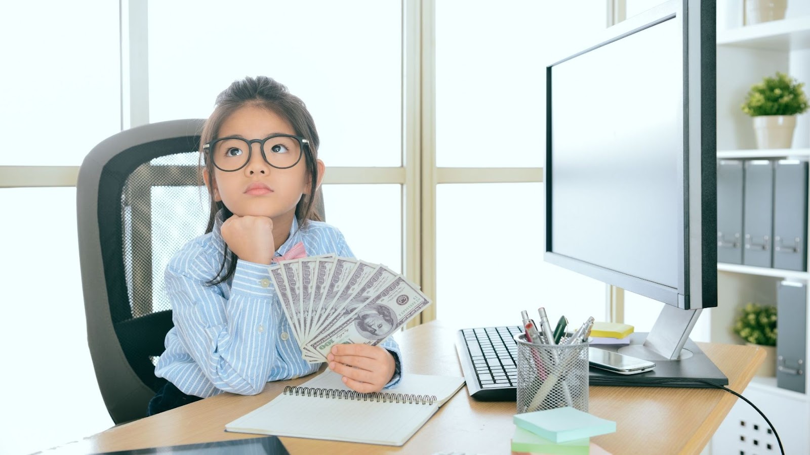 girl sitting at a desk holding money 