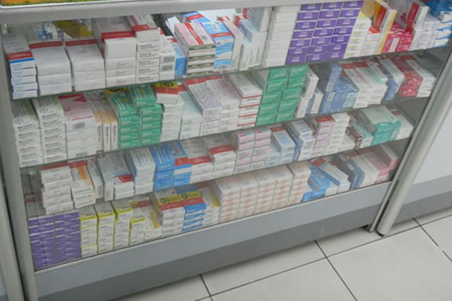A image mostra um checkout de farmácia cheio de medicamentos e nenhum produto de conveniência.