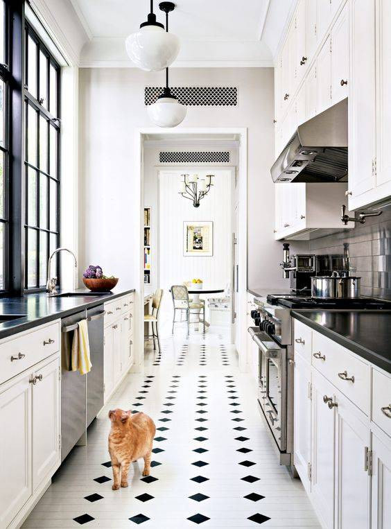 traditional galley kitchen with black and white finishes. white cabinets are complemented by stark black countertops and a black and white tile floor