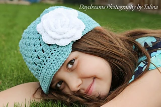 girl wearing a teal newsboy hat with white flower