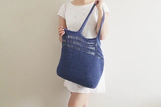 woman holding a blue crochet tote bag