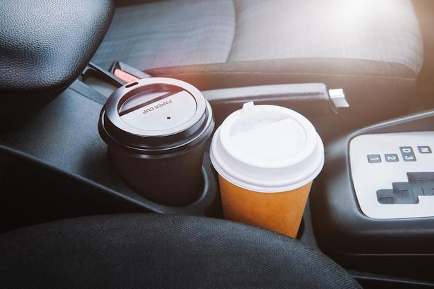 Paper coffee cup in a car two paper coffee cup standing inside the car between seats