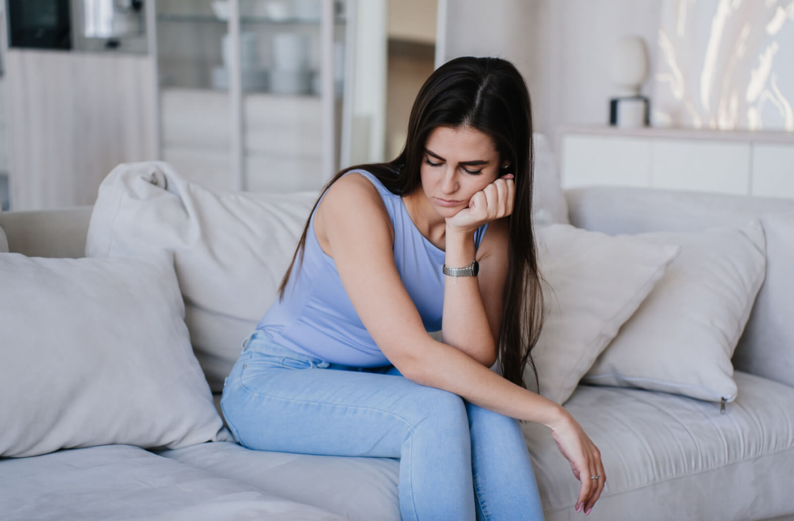 A woman sitting on a couch showing signs of depression.