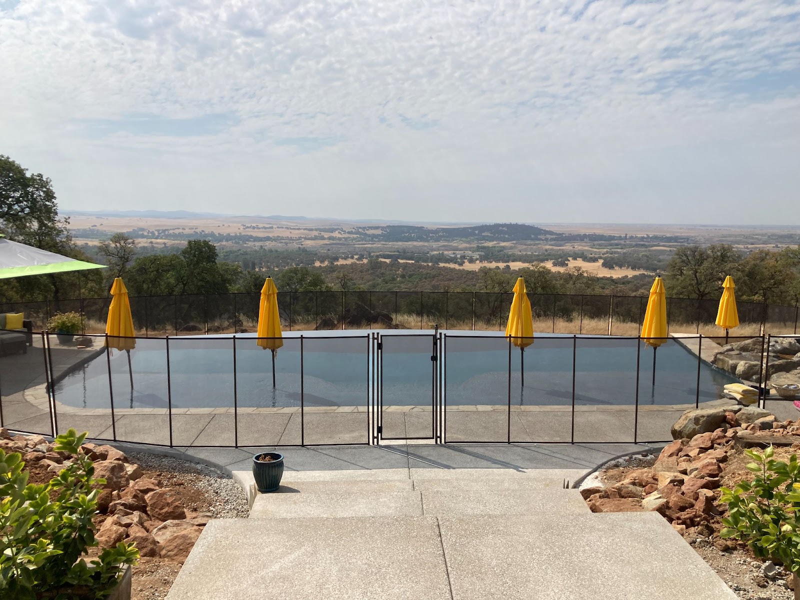 Black mesh removable pool fence installed around large swimming pool